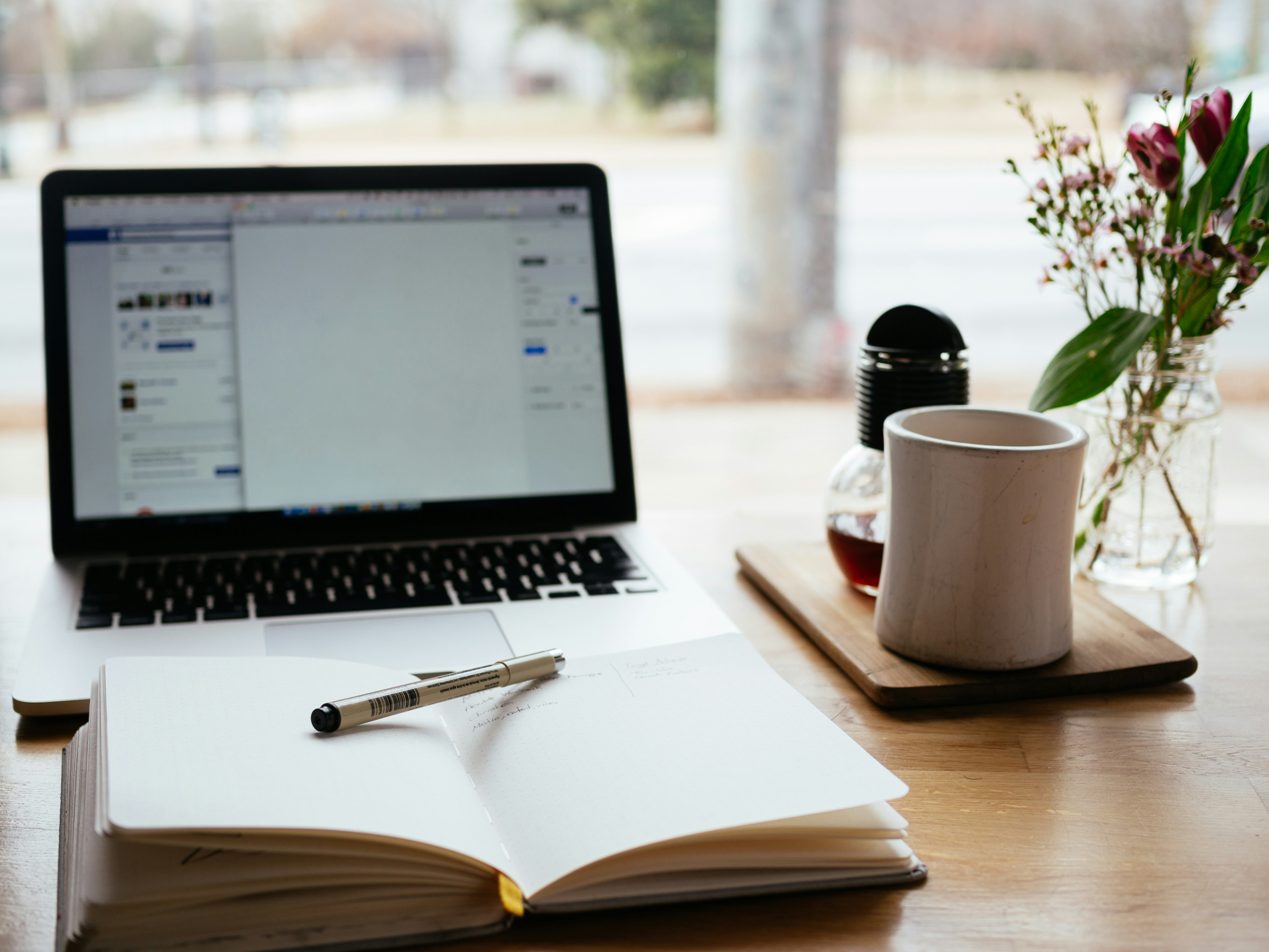 A laptop, notebook and coffee on a desk at night with a recorded lecture on screen