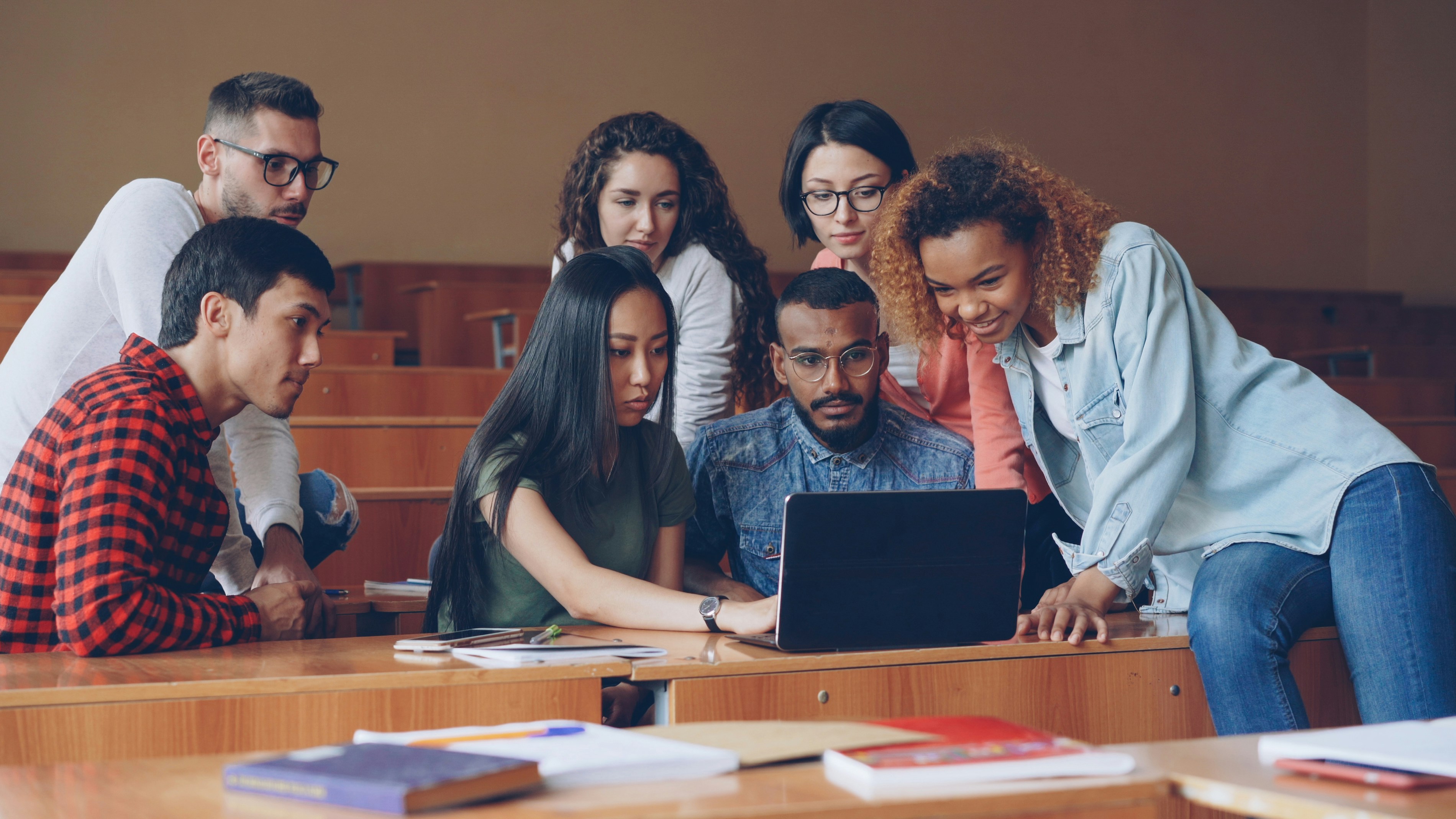 Group of students collaborating around a laptop in a university setting